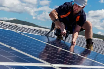 Man staat op het dak bij zonnepanelen